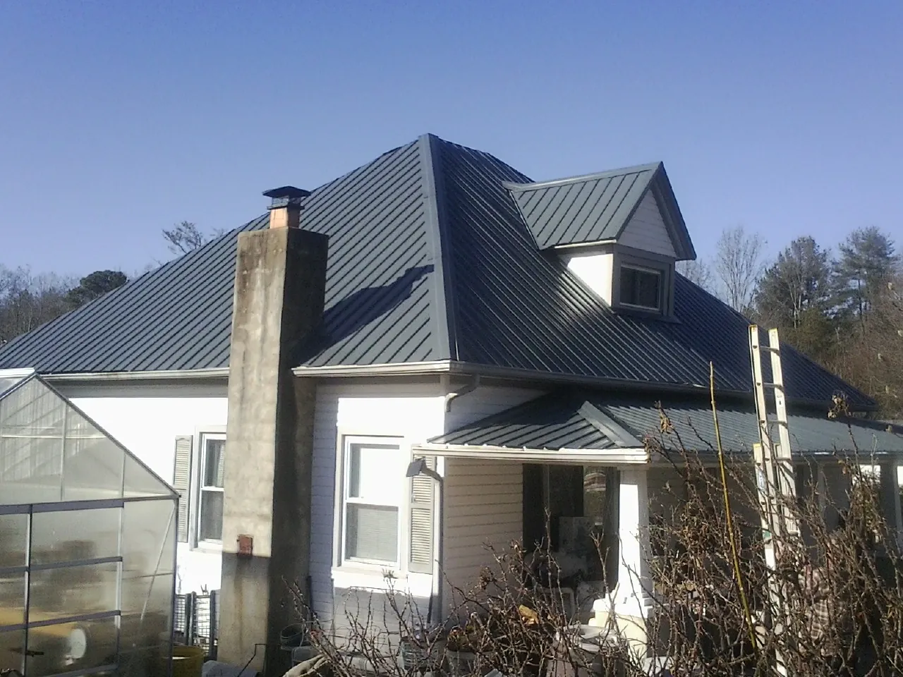 Dark blue standing seam metal roof on a white farmhouse with dormer — Slate & Tile Roof Repair by Roofing Brothers in Davis