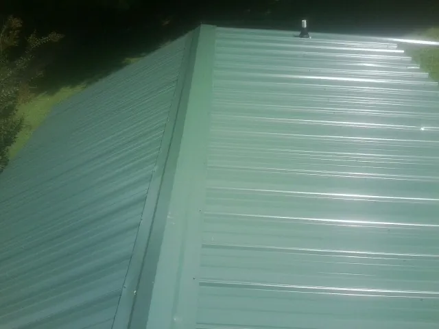 New green metal panels meeting at the ridge of a roof — Flat Roof Repair work by our crew in Davis